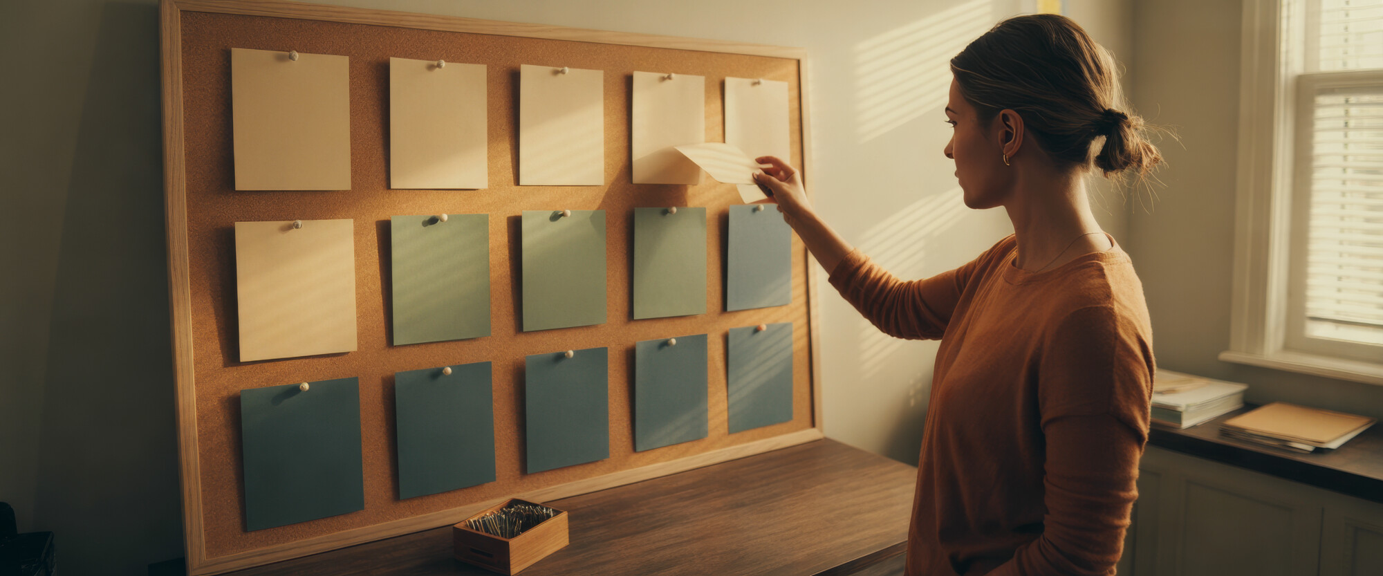 Home care agency owner pins planning cards in rows on a cork board in her office.